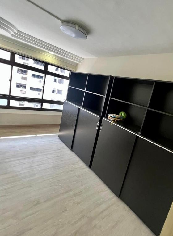 Matt black full-height storage run with open top shelves, in a bedroom with pale wood-grain flooring.