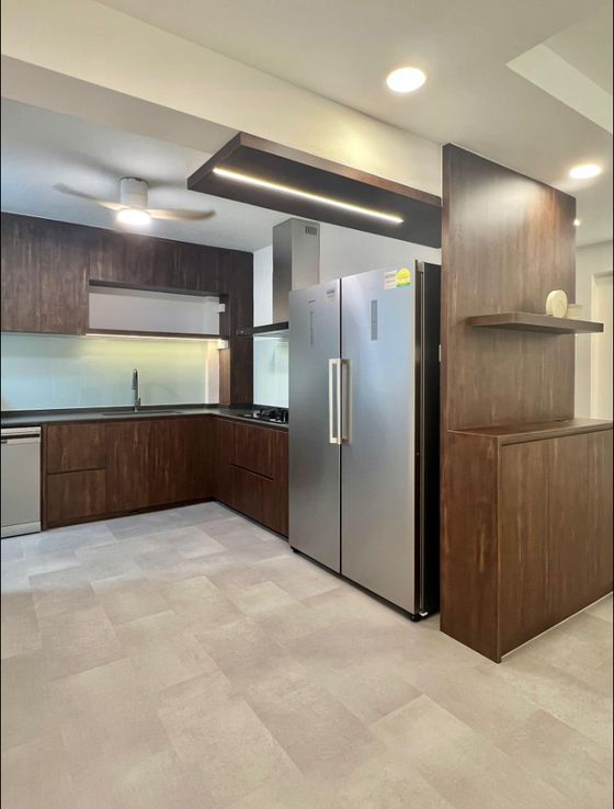 Dark wood-grain kitchen with a stainless fridge in a recessed housing, chimney hood, glass splashback and a matching display column.