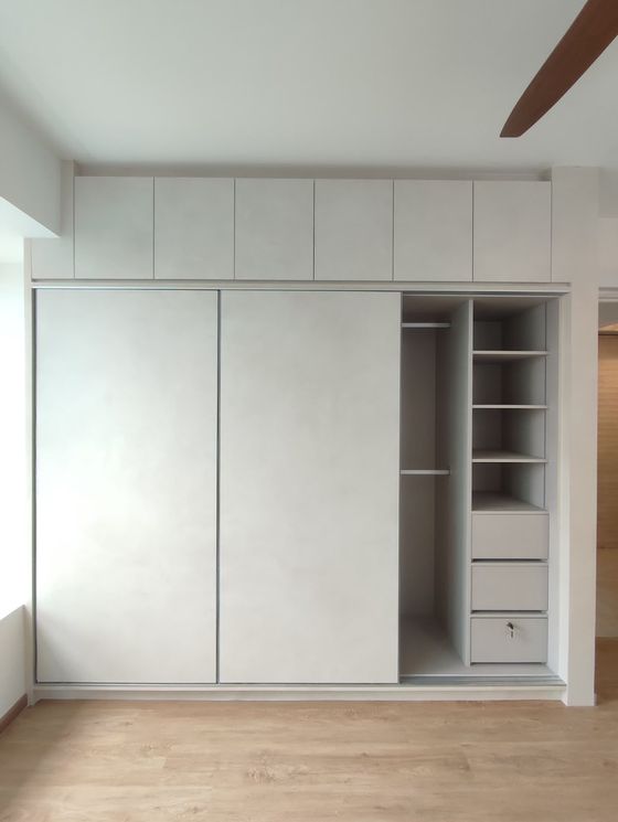 Pale concrete-effect sliding-door wardrobe with top boxes and an open shelf-and-drawer column.