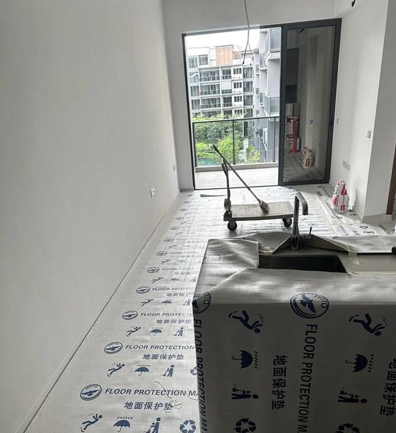 Printed floor-protection matting laid wall to wall in a flat, with the worktop and sink wrapped.