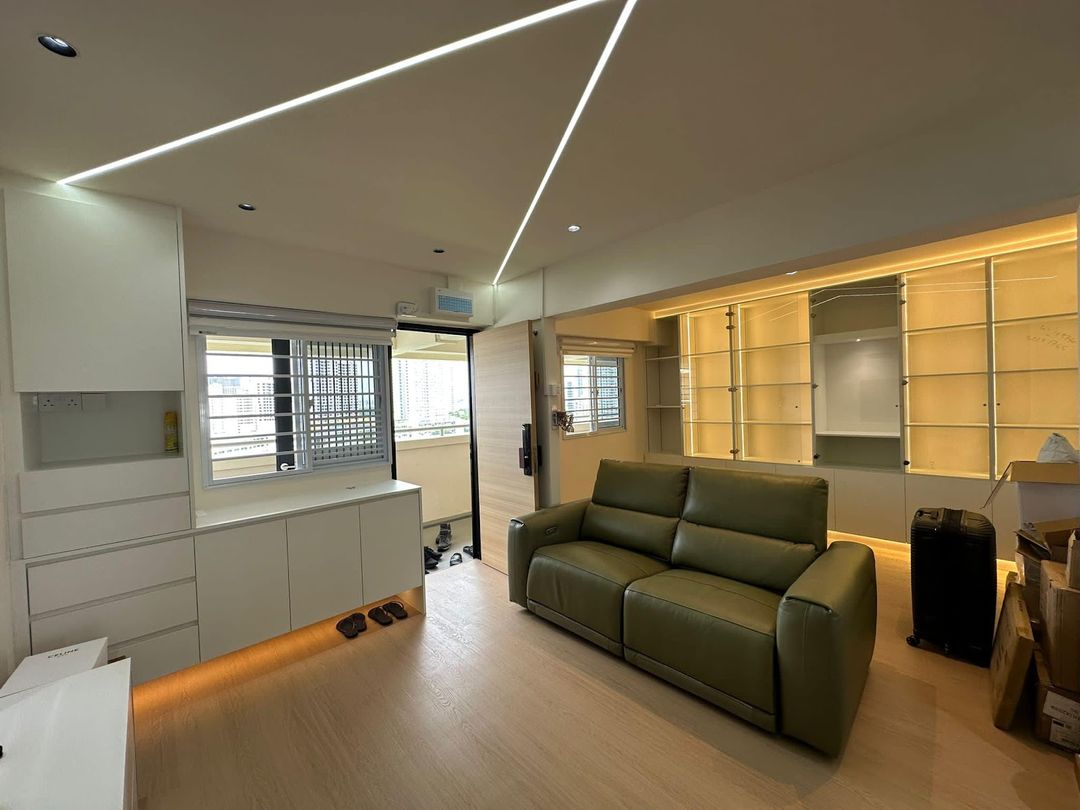Finished living room with an olive leather sofa, linear LED ceiling channels, glass-fronted display shelving and a white storage run, renovated by Startec.