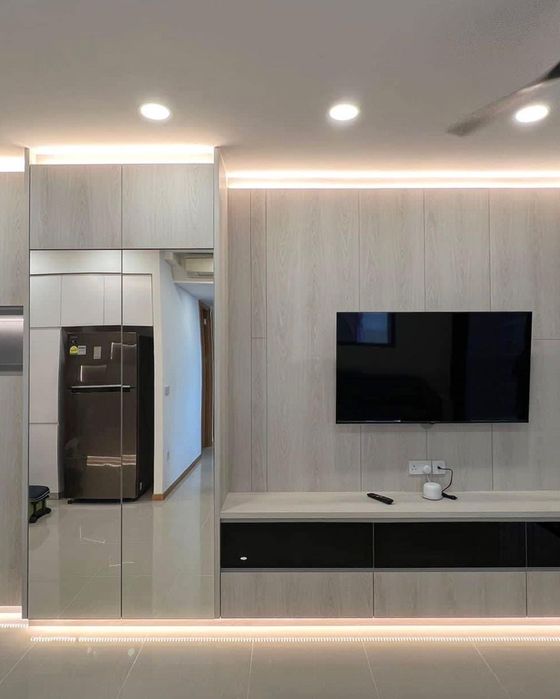 Living room TV feature wall in pale wood-grain with a black-drawer console, cove lighting and a full-height mirrored cabinet.